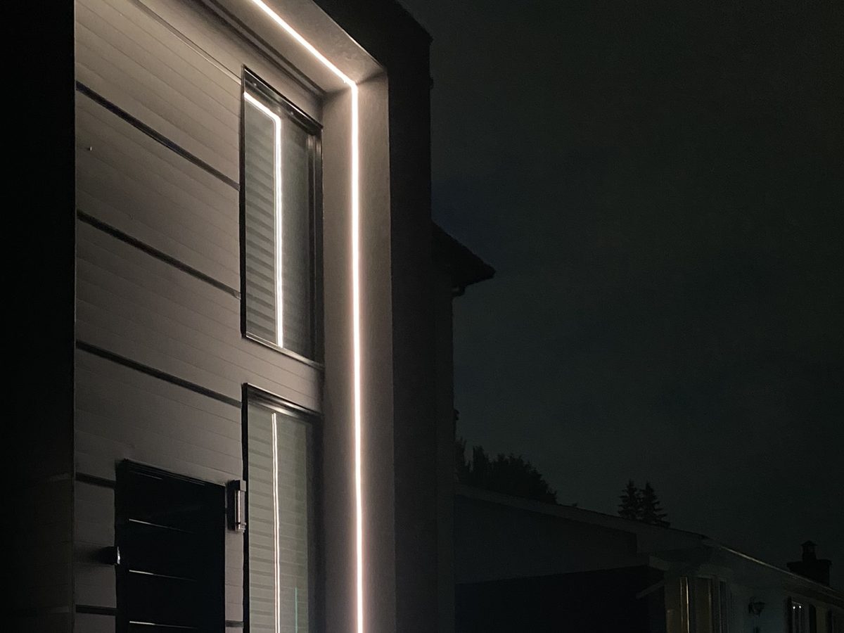 Même colonne en blanc : trait vertical blanc chaud sur une façade grise