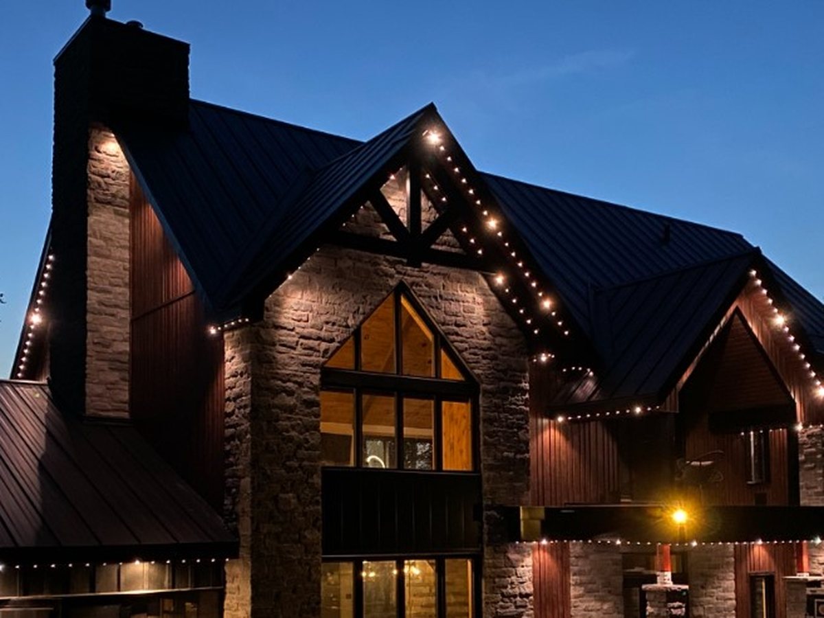 Chalet en pierre, pignon et rebords de toit soulignés de pixels blanc chaud