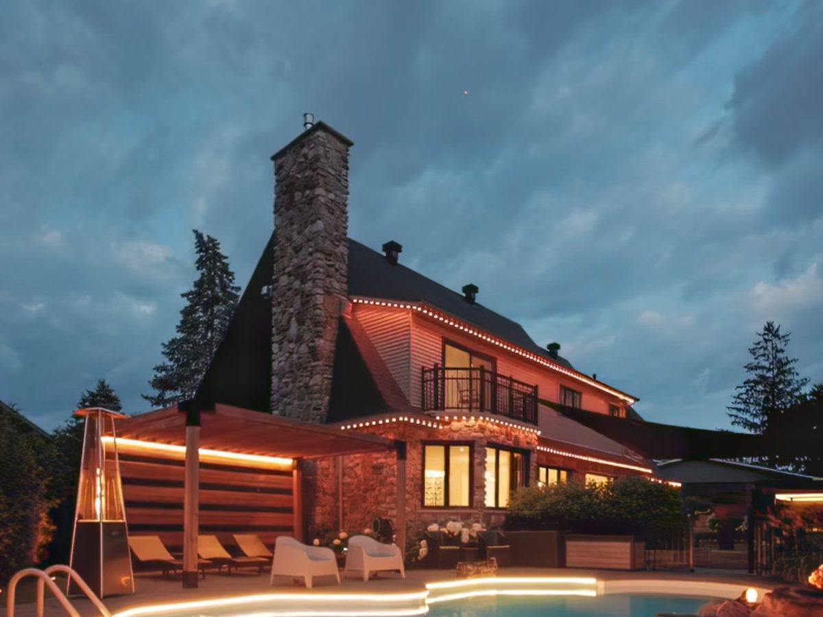 Maison de pierre au bord d'une piscine, toits soulignés de pixels blanc chaud