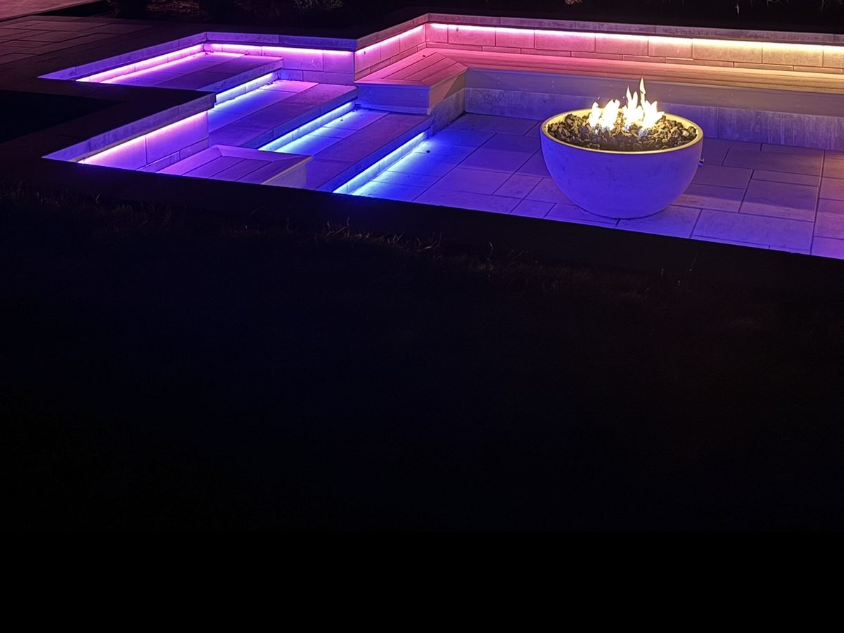 Murets et marches autour d'une piscine soulignés de bandes DEL rose et violet