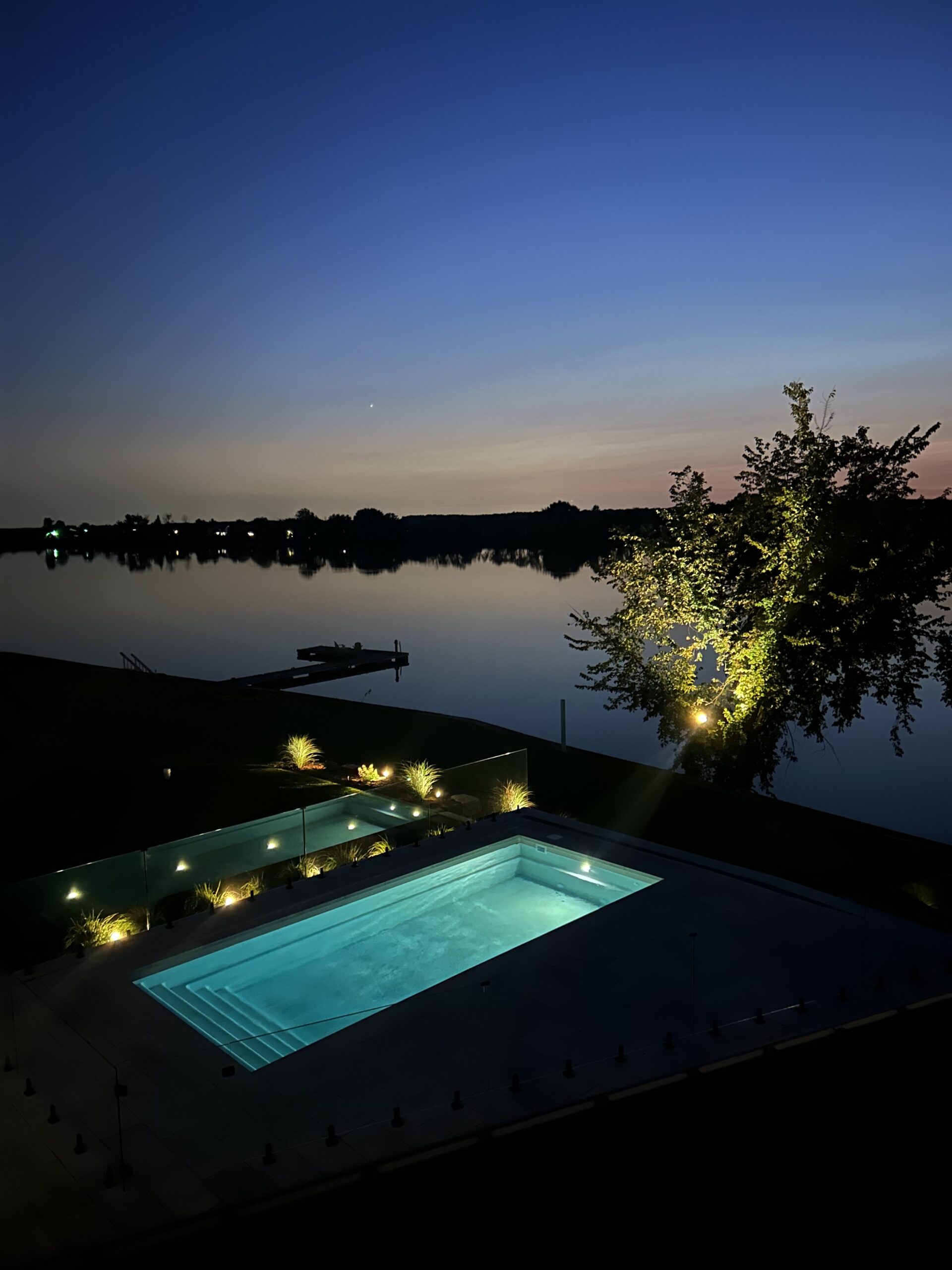 Fully equipped backyard: fire pit, low walls, swimming pool, and garden shed, all illuminated with colored lights